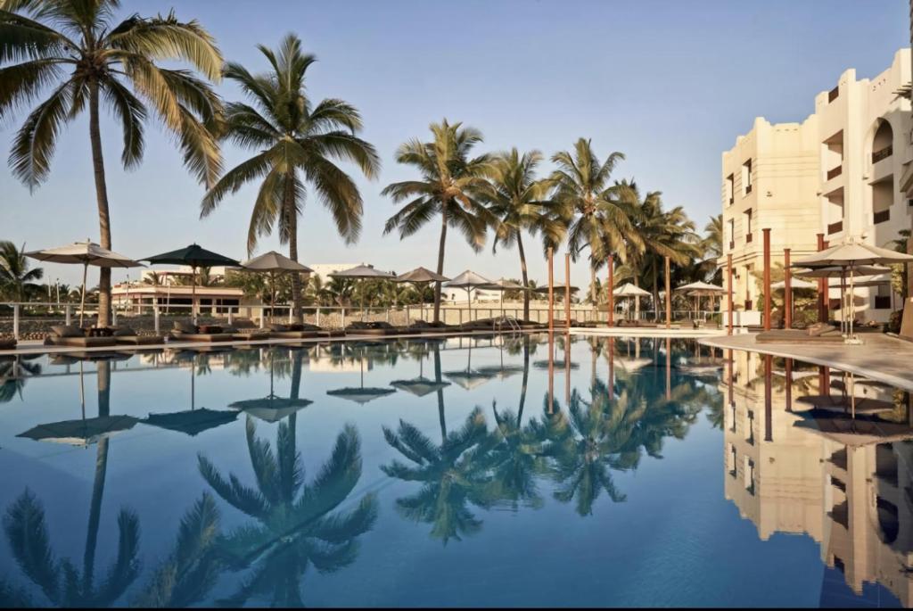 a pool at a resort with palm trees and buildings at Hawana salalah Apartment Acacia in Salalah