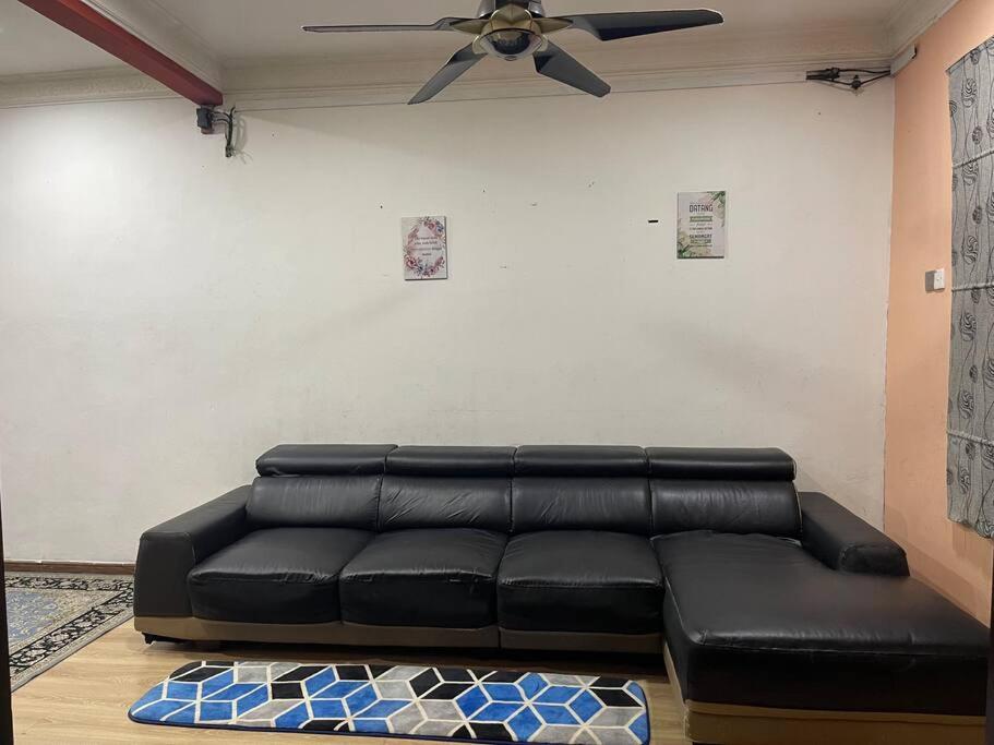 a black leather couch in a living room with a ceiling fan at DakNan Homestay Duyong in Malacca