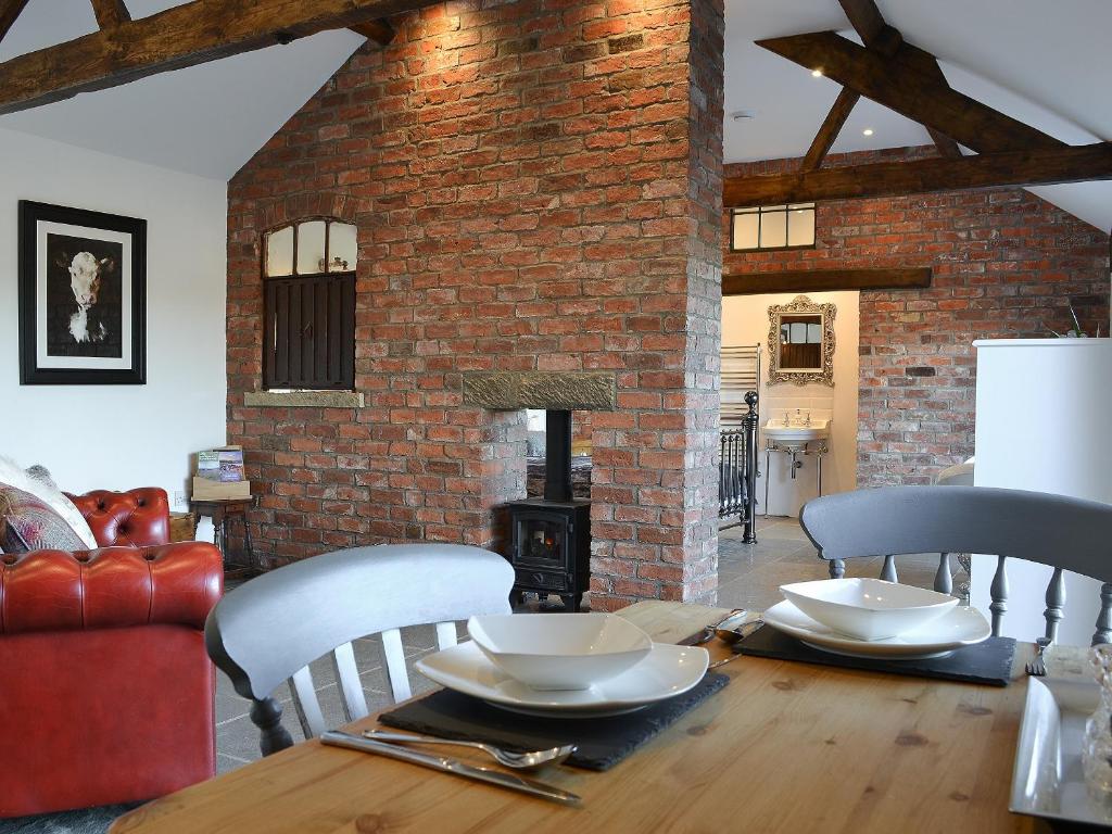 a living room with a table and a brick wall at Sunset Barn - Uk12855 in Normanby