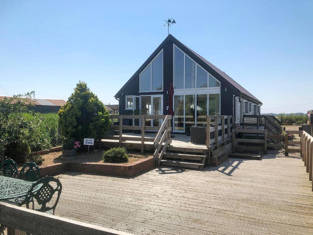 a black house with glass windows and a wooden deck at Moorings House in Fritton