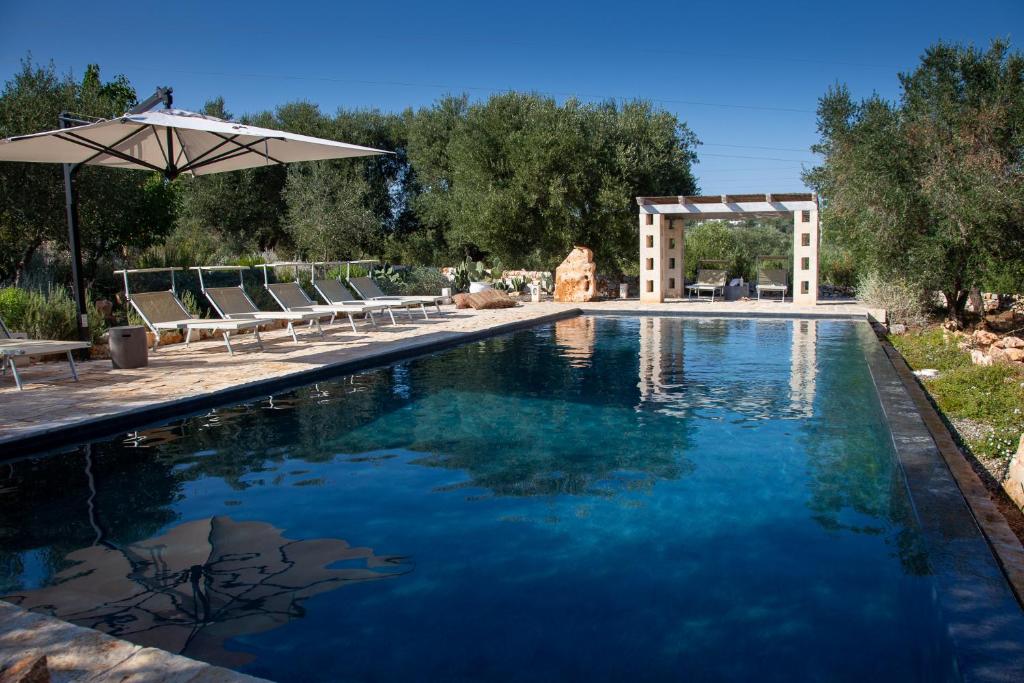 une piscine avec des chaises et un parasol dans l'établissement Casa Amahoro, à Ostuni