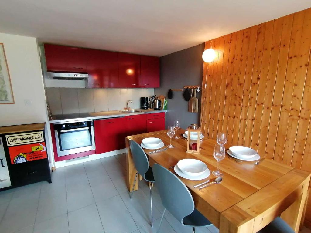 eine Küche mit einem Holztisch und roten Schränken in der Unterkunft Appartement Le Grand-Bornand, 4 pièces, 6 personnes - FR-1-241-63 in Le Grand-Bornand