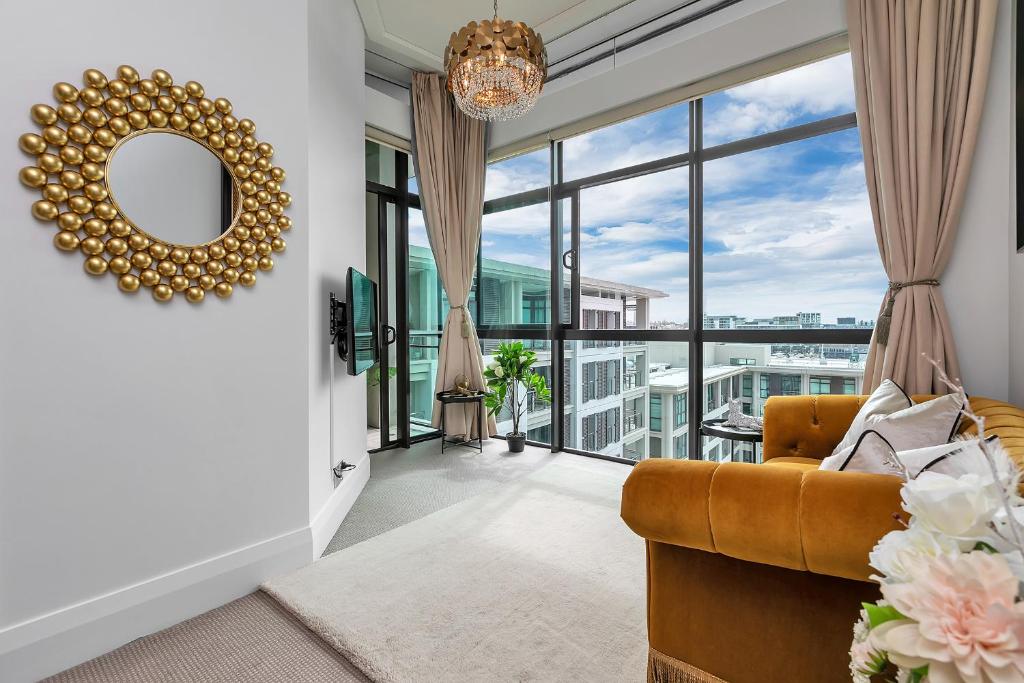 a living room with a couch and a large window at The Golden Hour Penthouse in Auckland