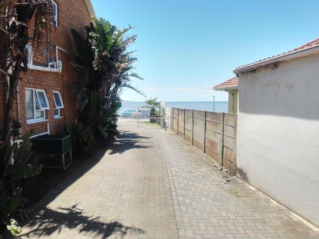 an empty street with a brick building and the ocean at 5 Bayview Gonubie Seaside in Gonubie