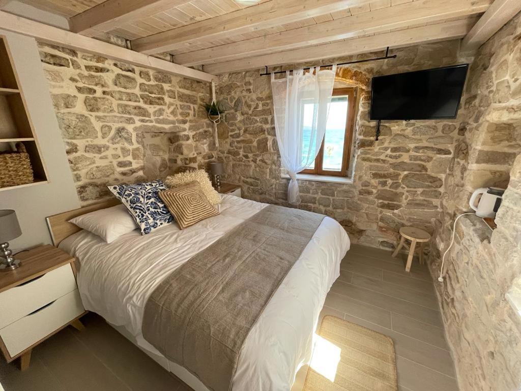 um quarto com uma cama e uma parede de pedra em Knez apartments and rooms em Kaštela