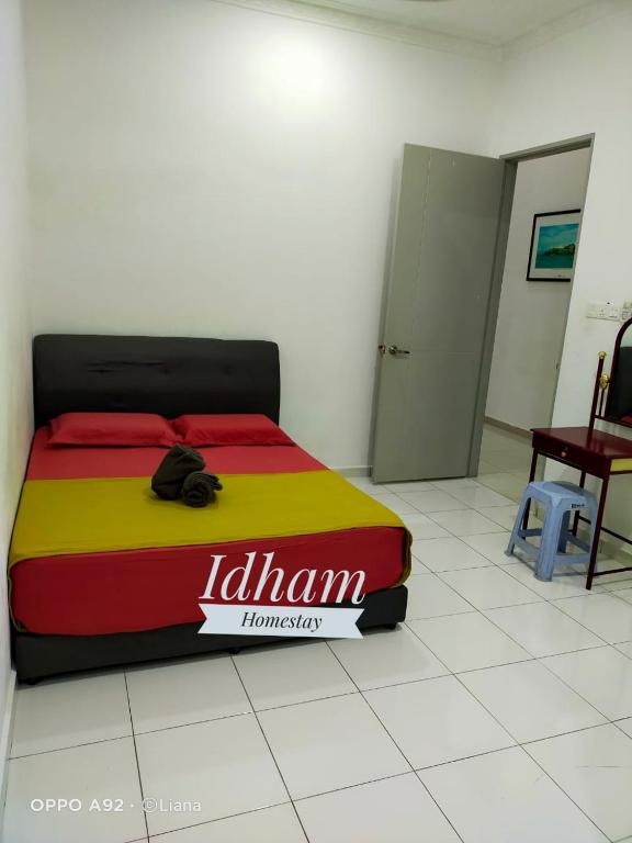 a bed in a room with a yellow and red blanket at Idham homestay in Ipoh