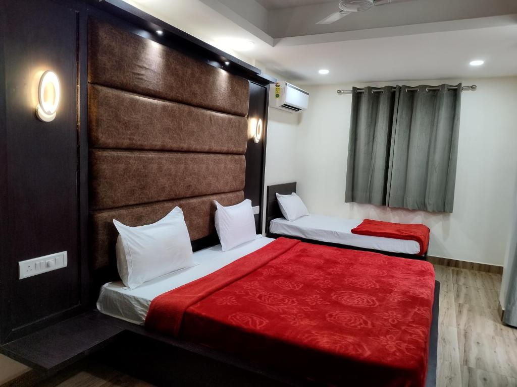 two beds in a hotel room with a red blanket at C V Inn in Baga