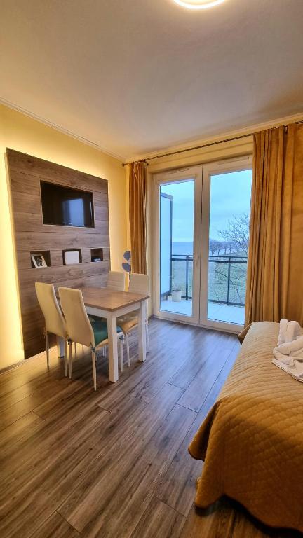 een slaapkamer met een bed en een tafel met stoelen bij Apartament "Złoty relaks" tuż przy plaży z balkonem z widokiem na Hel i hamakami in Puck