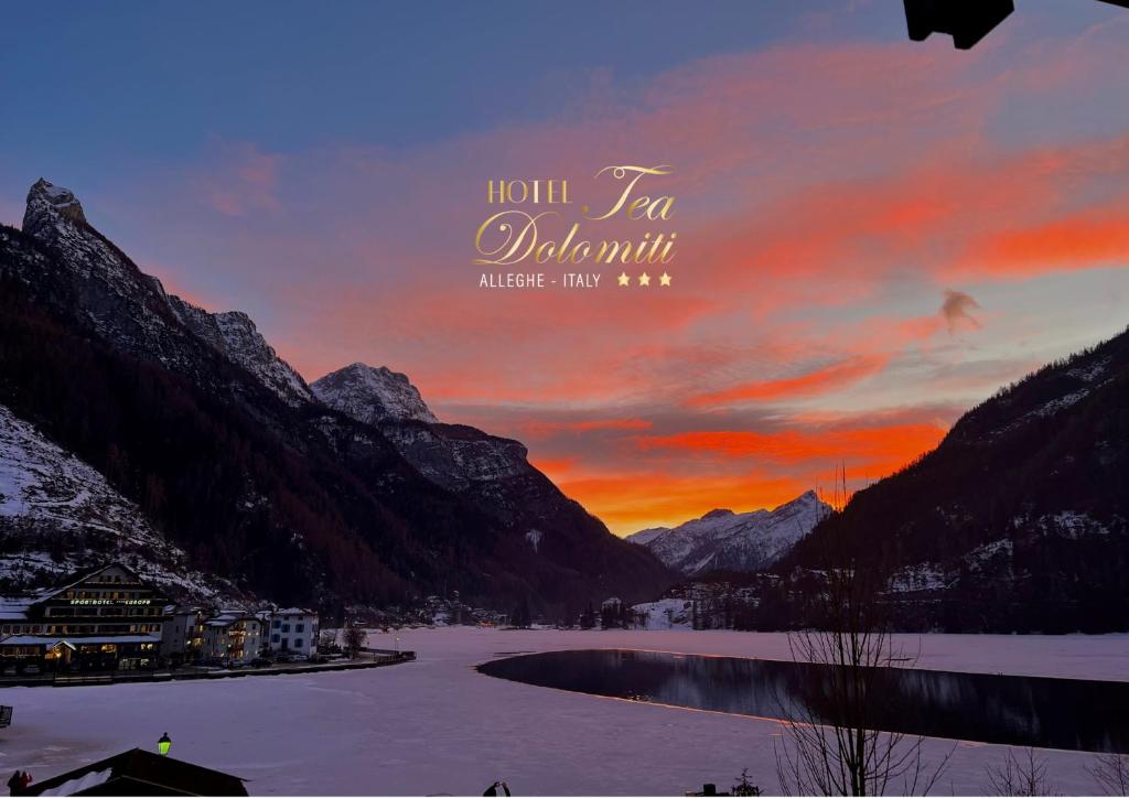 una puesta de sol en las montañas con un lago y montañas en Hotel TEA Dolomiti, en Alleghe