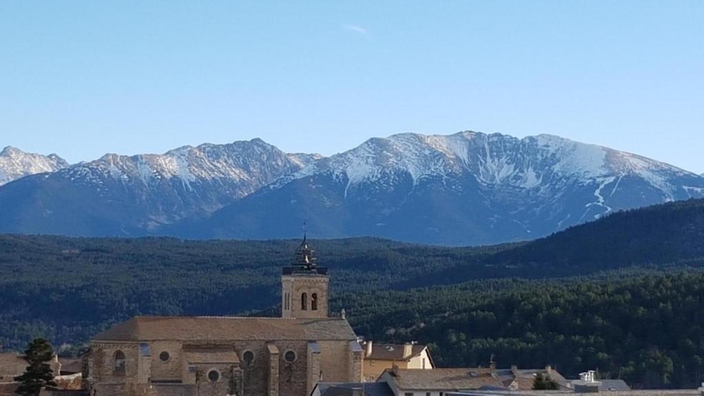 an old church with snow covered mountains in the background at Au coeur des Angles in Les Angles