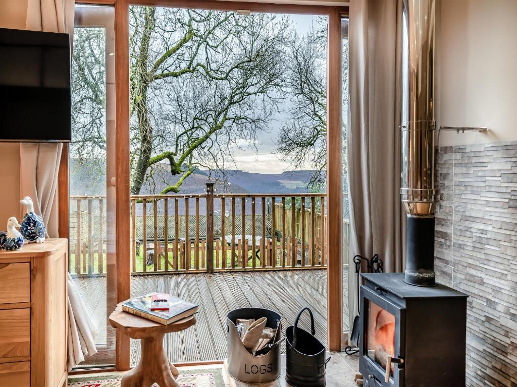 a living room with a fireplace and a balcony with a view at Goshawk Lodge in Abercarn