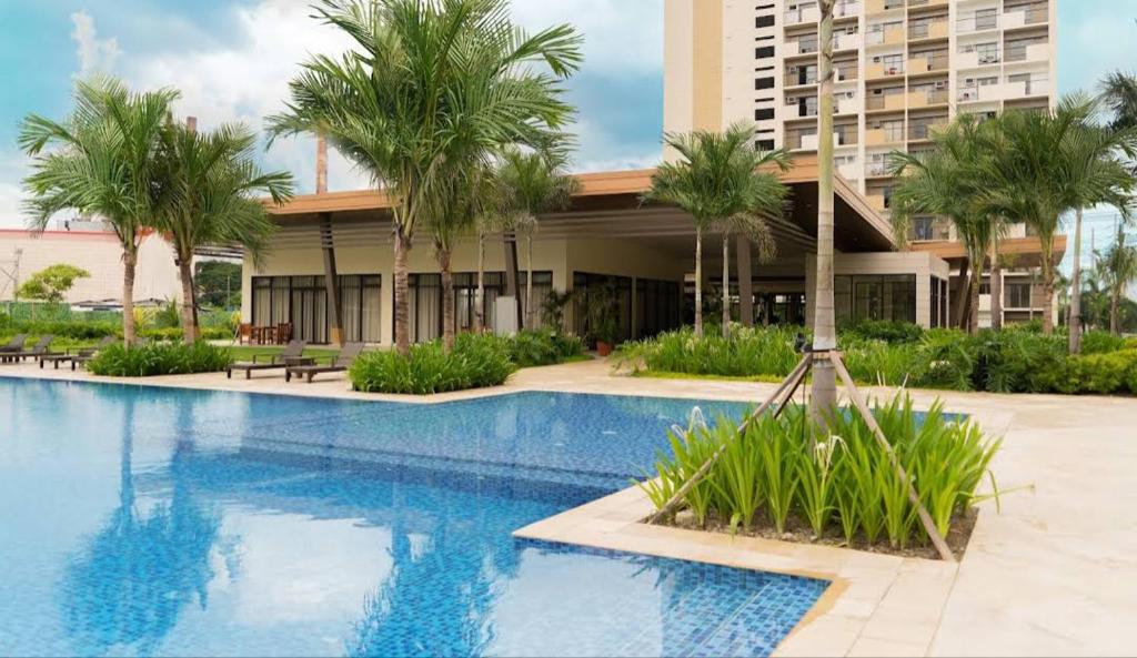 einem Pool mit Palmen vor einem Gebäude in der Unterkunft Alabang Condominium PHC in Manila