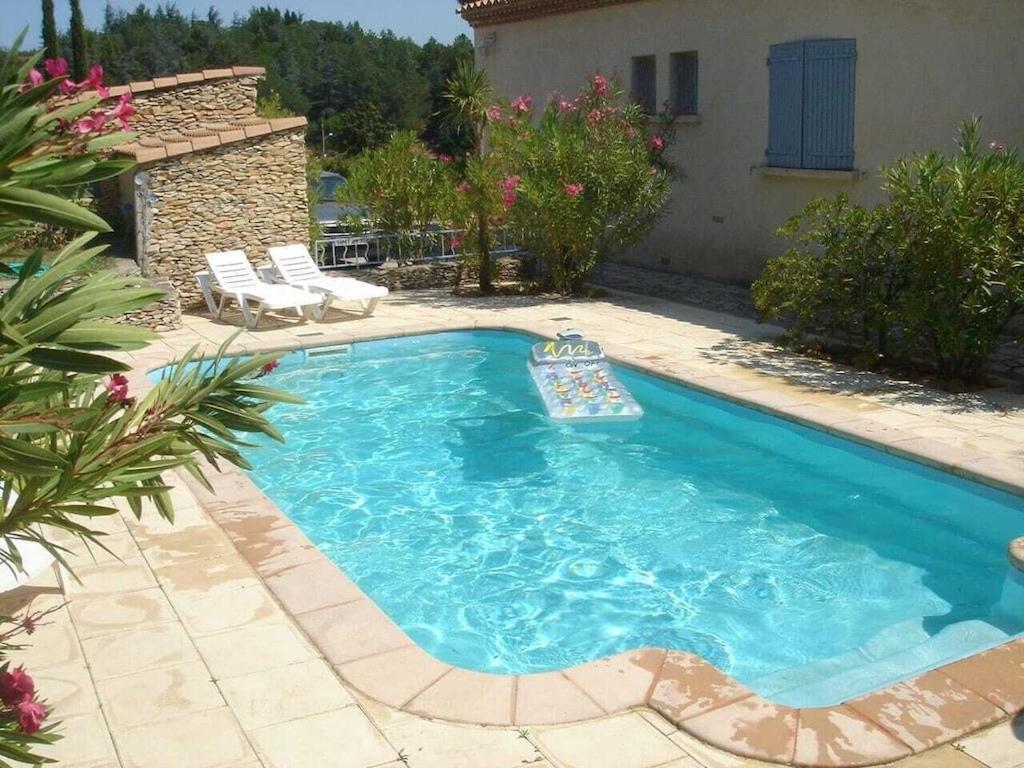 a swimming pool with a raft in a yard at La maison de vacances de Campoussin in Montfrin