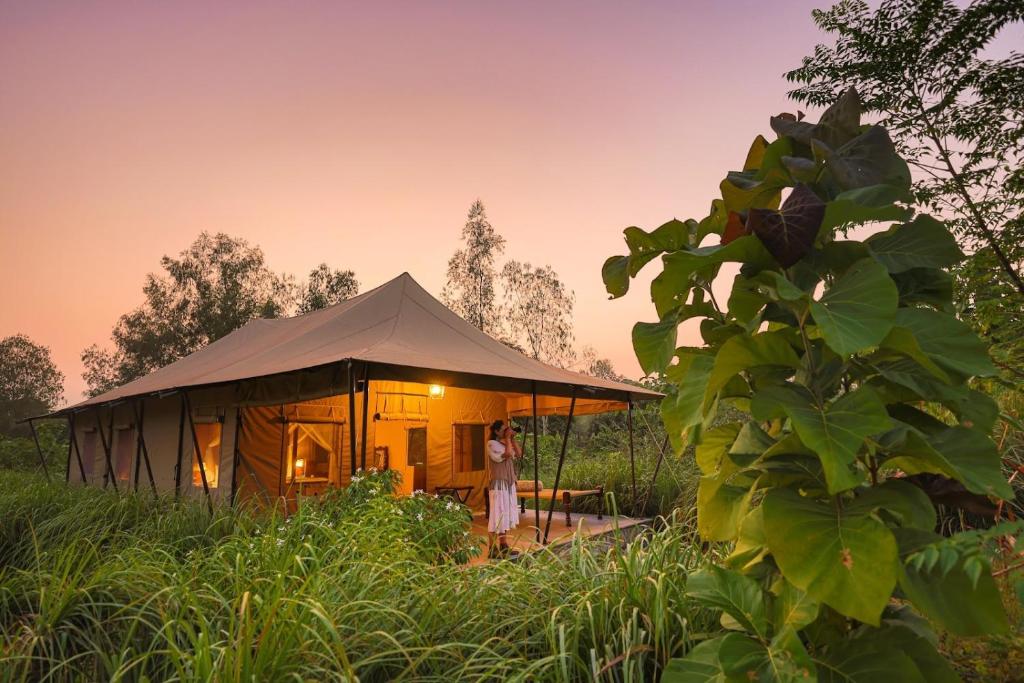 Una donna in piedi davanti a una tenda in un campo di Aalia Jungle Retreat and Spa, Bandarjudh, Haridwar - Araiya Anthology a Dehradun