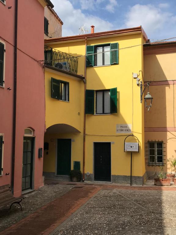 a yellow building with green windows in a street at Casa Camilla in Montemarcello