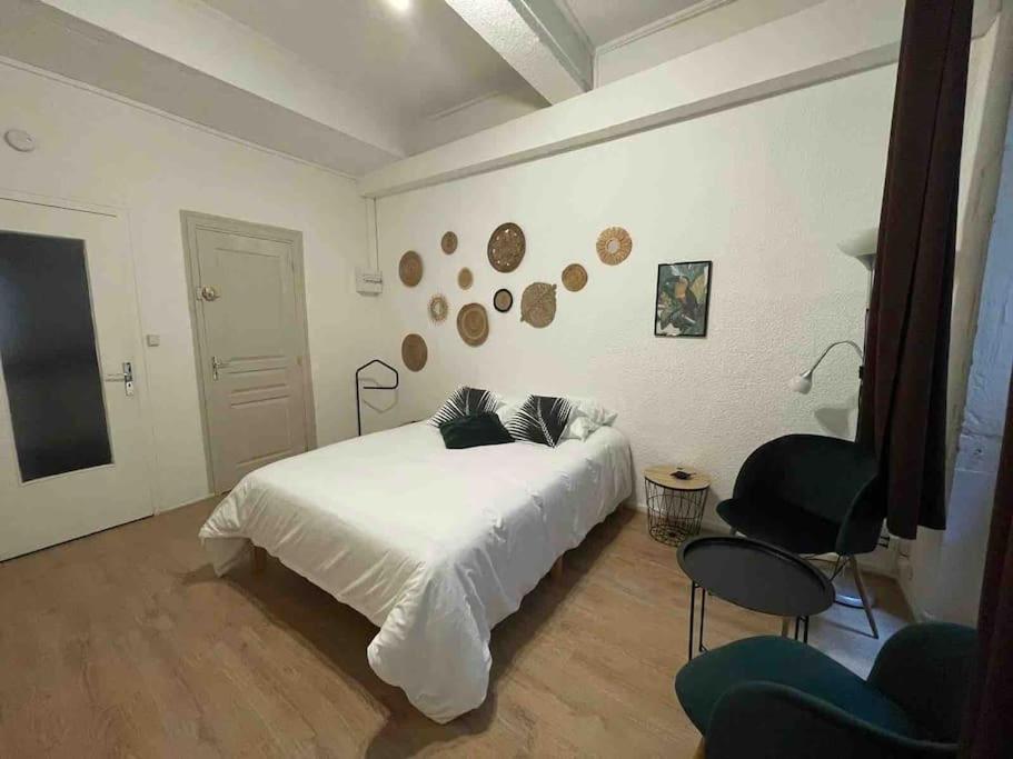 een slaapkamer met een wit bed en een stoel bij LA GRANDE COTE in Lyon