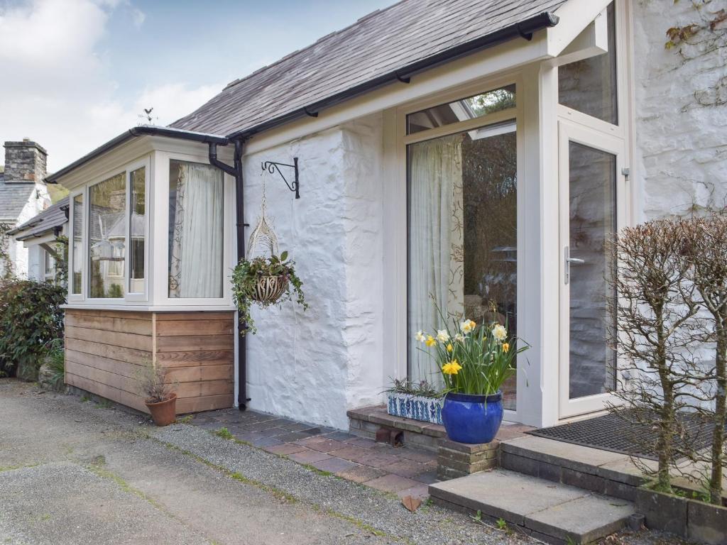 uma casa branca com uma porta da frente com flores em Tucking Cottage em Treffgarne
