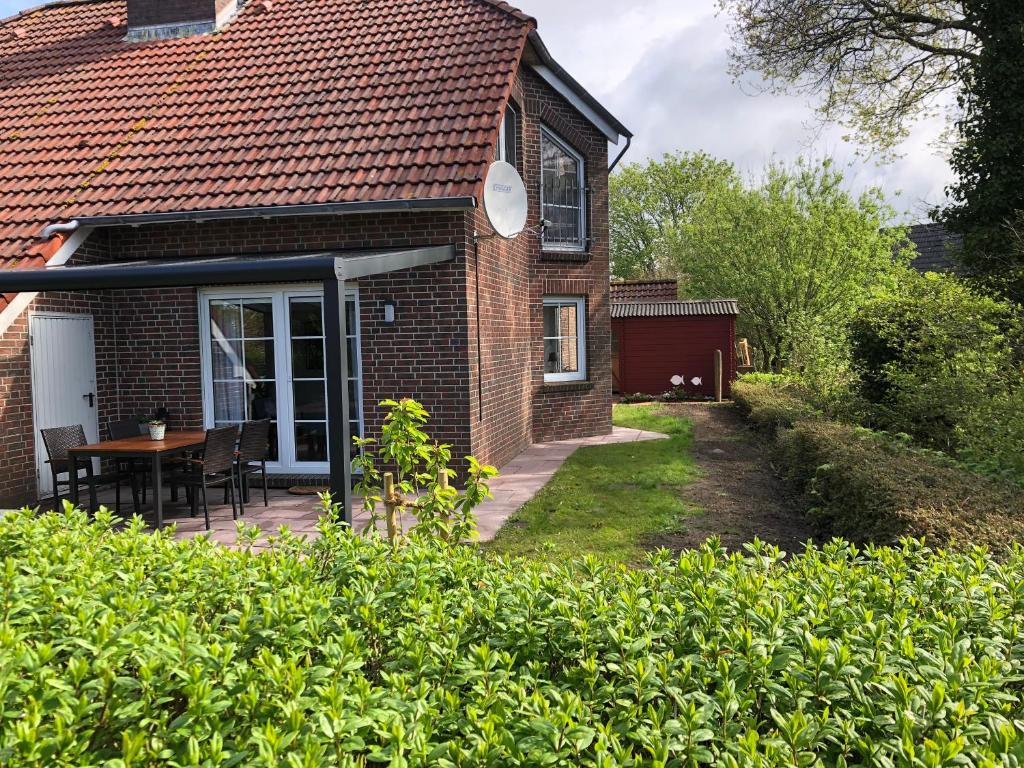 ein Backsteinhaus mit einer Terrasse und einem Tisch in der Unterkunft Haus Strandflieder in Greetsiel