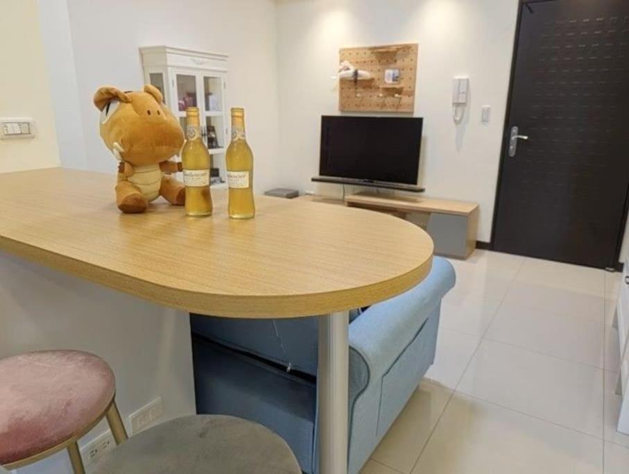 a stuffed animal sitting on a table with two bottles of wine at Luxury Studio in the vibrant Kaohsiung Arena MRT in Kaohsiung