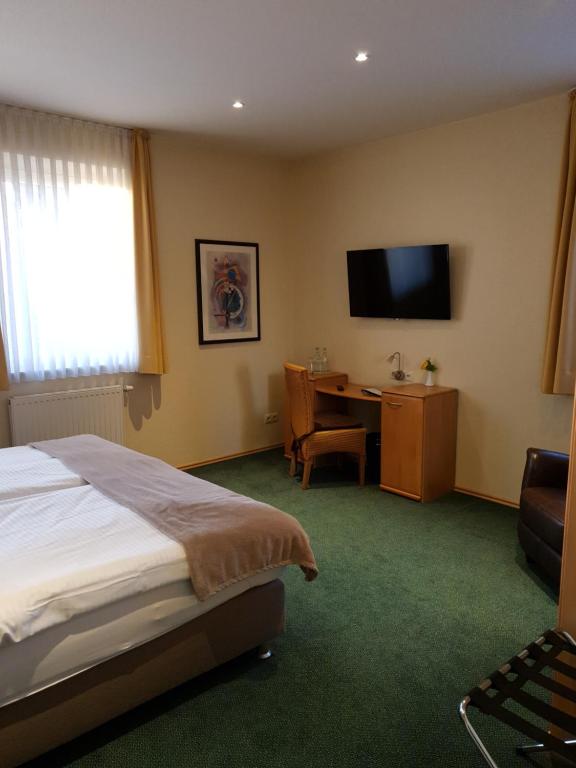 Schlafzimmer mit einem Bett, einem Schreibtisch und einem TV in der Unterkunft Hotel Knipper in Lastrup