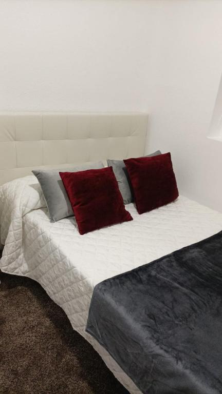 a bed with red and grey pillows on it at Habitación cerca centro de Madrid in Madrid