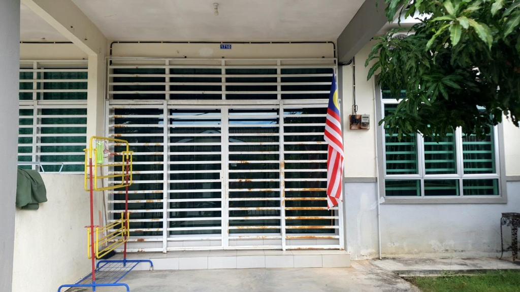 a window with blinds on a house with a flag at Homestay Ahmad Kuala Kangsar in Kuala Kangsar