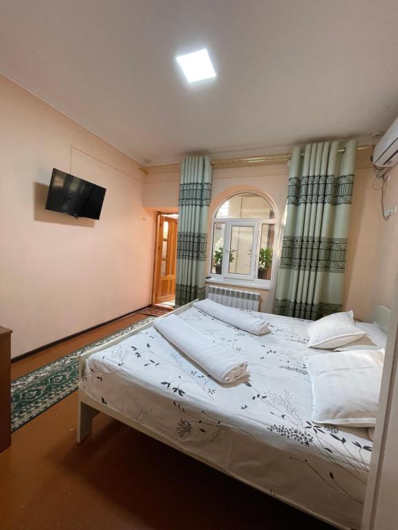 a bedroom with a large bed with a tv on the wall at Hotel Al Mansur in Bukhara