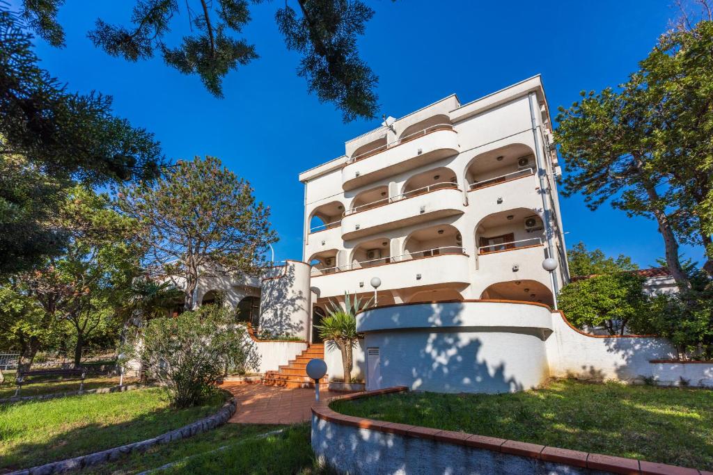 a white building with trees in front of it at Guest House Agava in Crikvenica