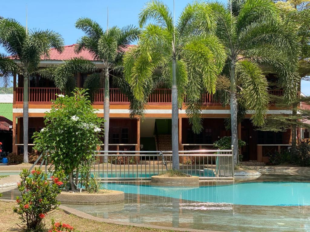 a building with palm trees and a swimming pool at PANGKOR PURNAMA CHALET in Pangkor