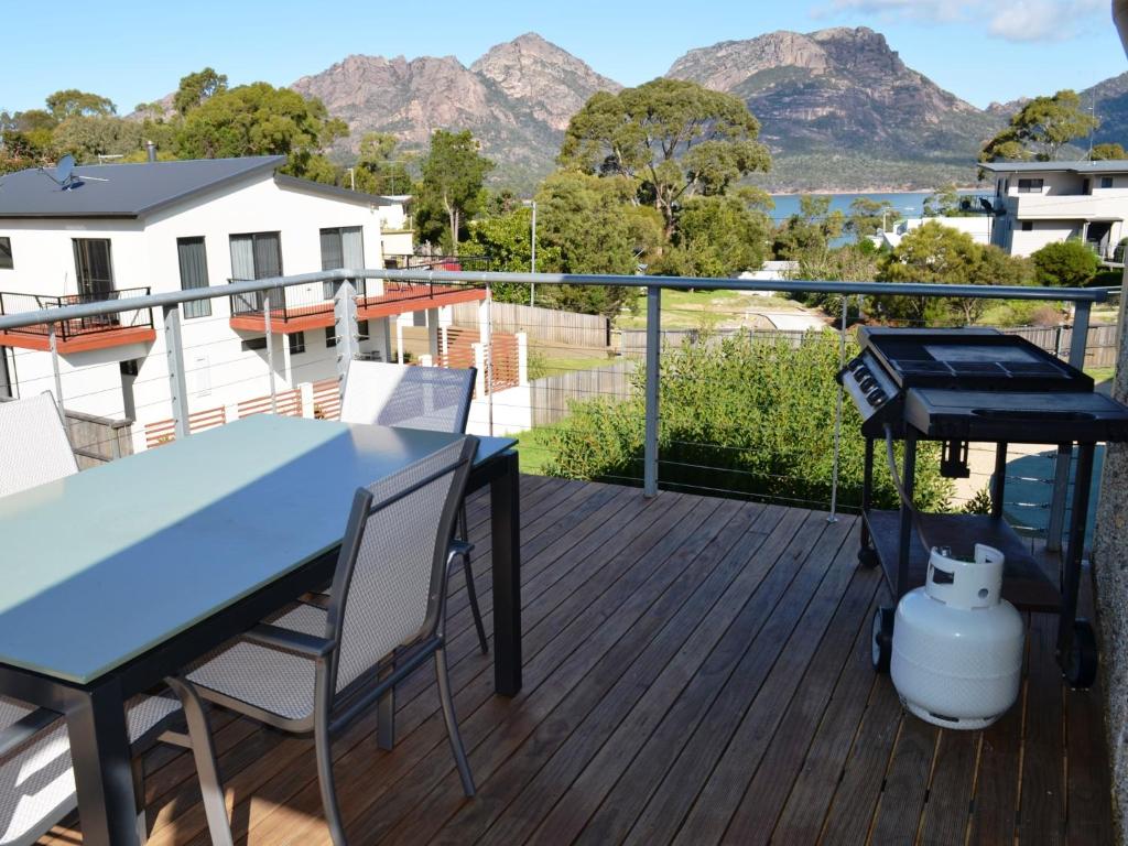a deck with a table and chairs and a grill at Pebble Shack in Coles Bay