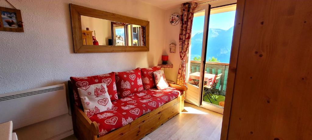 a living room with a couch with red and white pillows at STUDIO 4 personnes in Les Prés