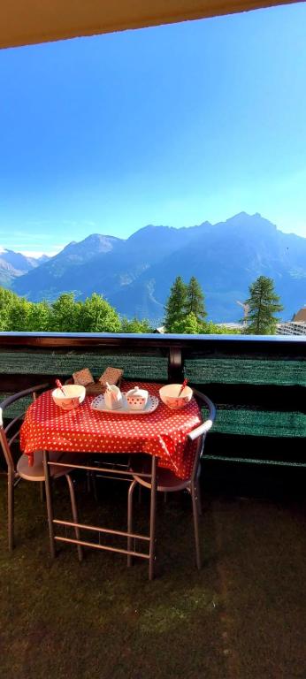 une table et des chaises assises sur un balcon avec vue sur les montagnes dans l'établissement STUDIO 4 personnes, à Les Prés