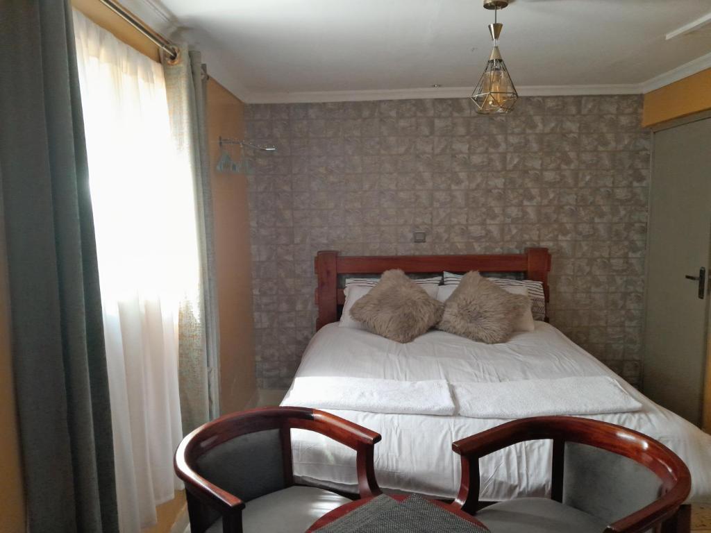 um quarto com uma cama com 2 cadeiras e uma janela em Sparkle Residency em Nairobi