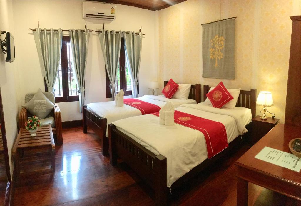 a bedroom with two beds with red and white sheets at Luang Prabang Pangkham Lodge in Luang Prabang