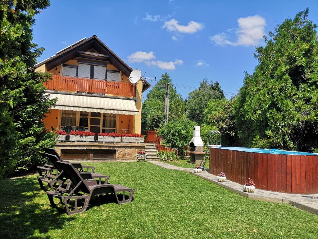 a house with two benches in the yard at Aranyhal Vendégház in Sukoró