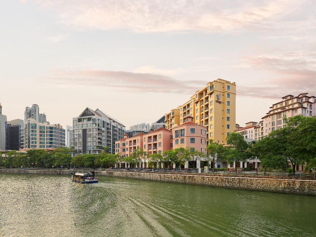 a boat on a river in a city with buildings at Village Residence Robertson Quay by Far East Hospitality in Singapore