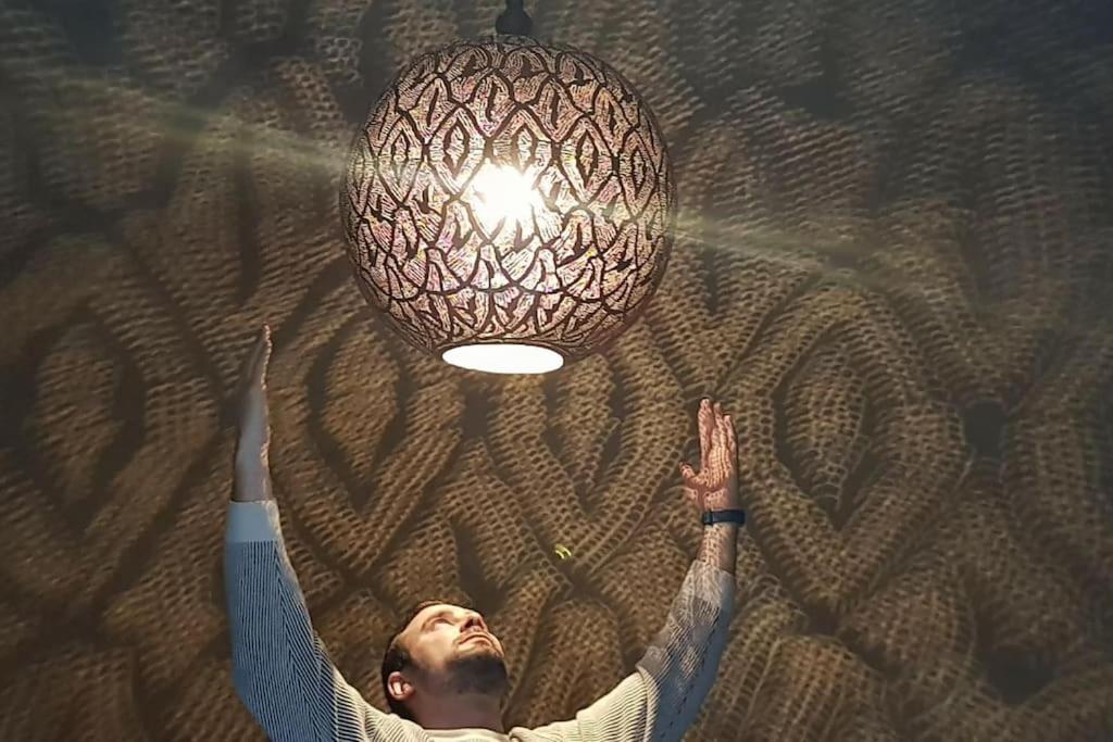 un homme atteint une lumière sur un plafond dans l'établissement House in the old Medina of Fez, à Fès al Bali