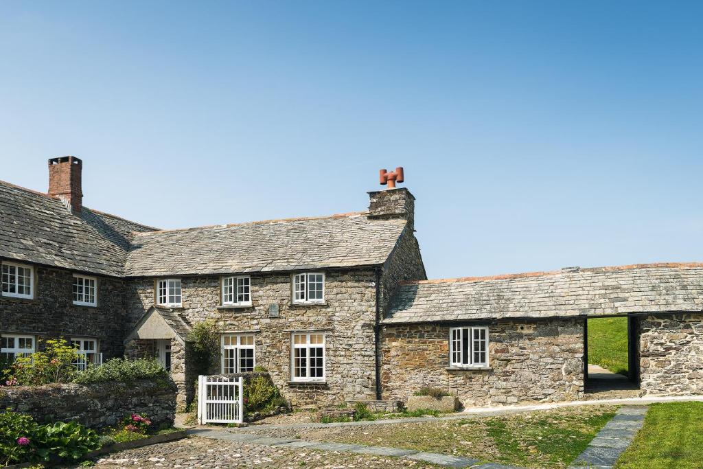 an exterior view of a stone house with white windows at Trevigue Farm in Crackington Haven