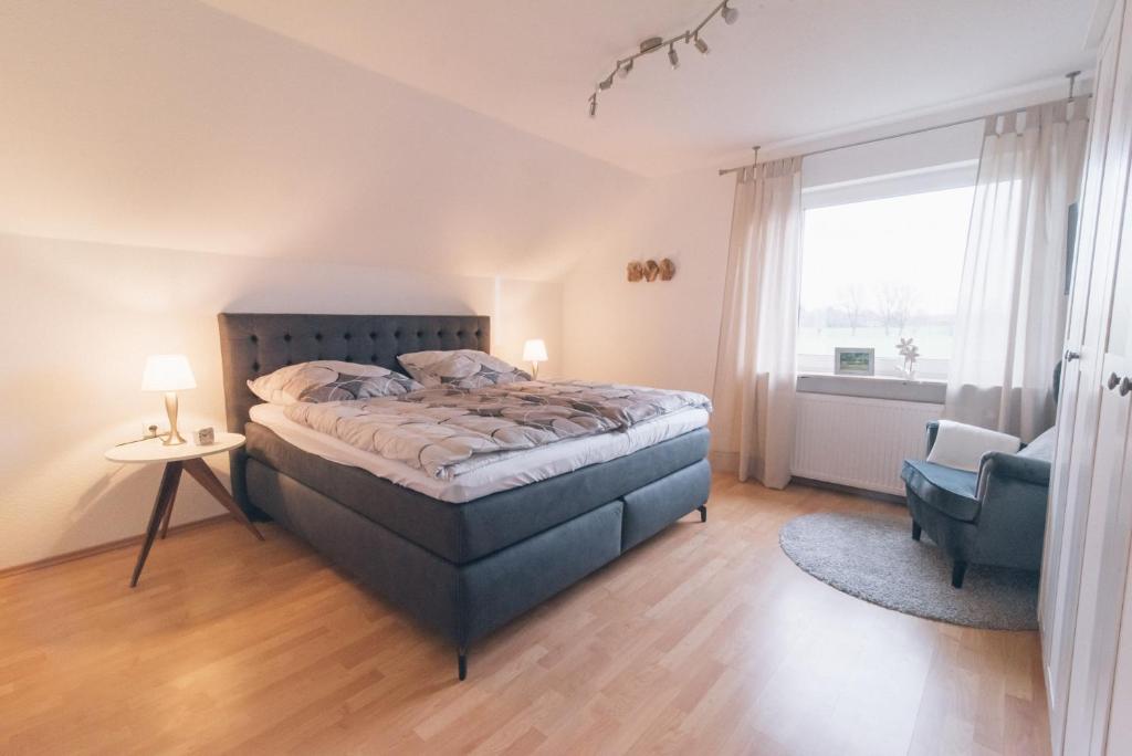 a bedroom with a bed and a chair and a window at Ferienwohnung In den Wiesen in Wesel