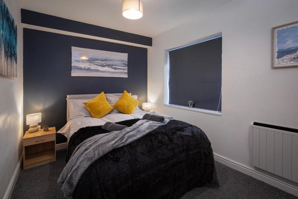 Un dormitorio con una cama con almohadas amarillas y una ventana en Bank Street Apartment 5, en Blackpool