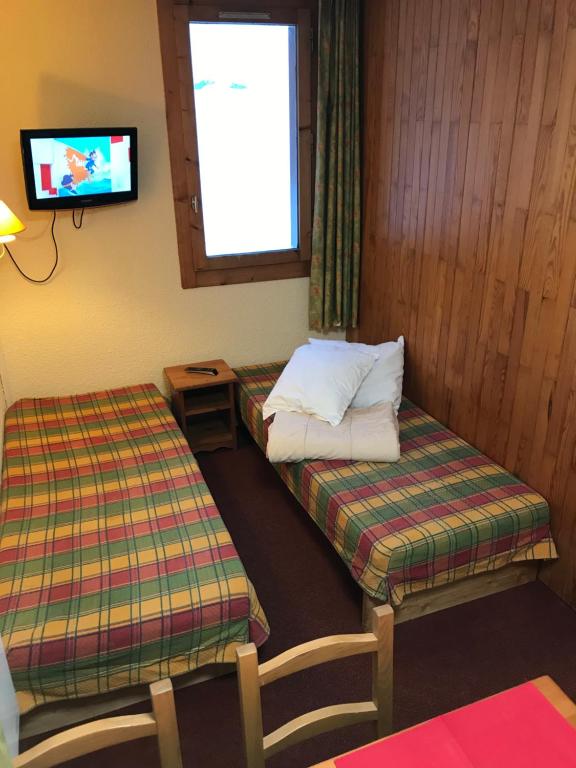 a room with two beds and a tv on the wall at appartement ski au pied in Valmorel