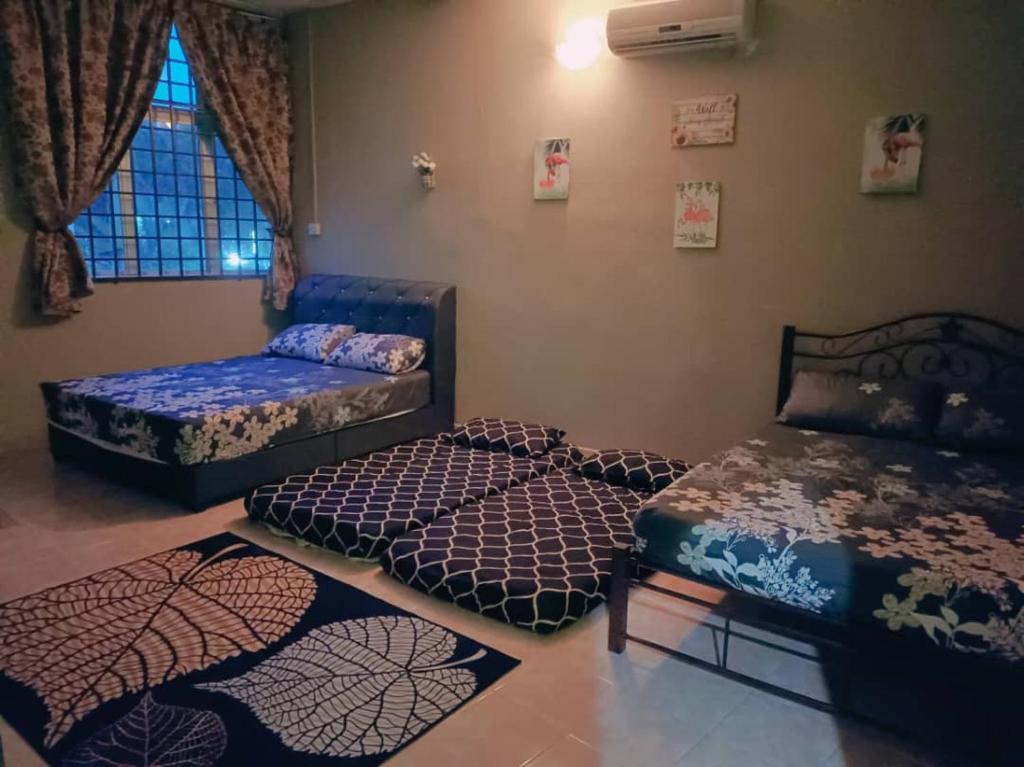 a room with three beds and a couch and a window at D'Diana Homestay in Port Dickson
