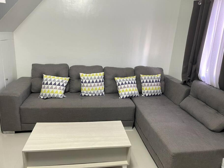 a living room with a gray couch with four pillows at 4 - Affordable 2-Storey House in Cabanatuan City in Cabanatuan