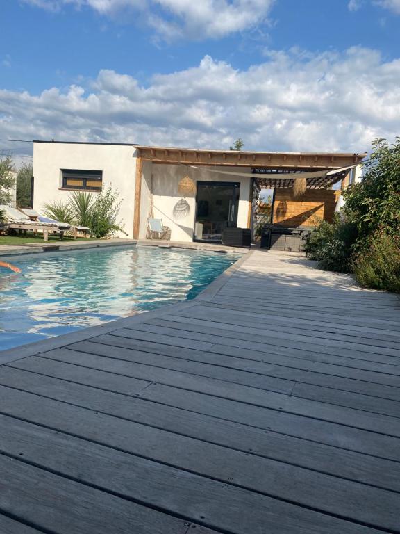 a swimming pool with a wooden walkway next to a house at le pool house in Nîmes