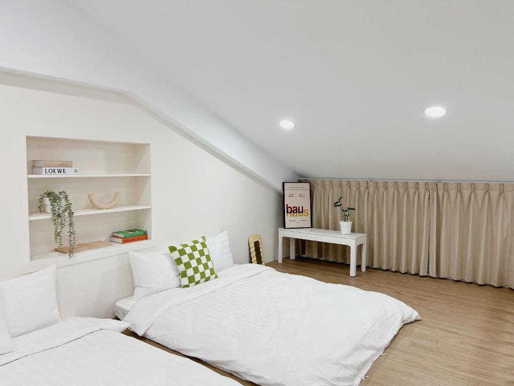 Soda White Tainan Homestay في تاى نان: غرفة نوم بيضاء مع سرير وطاولة