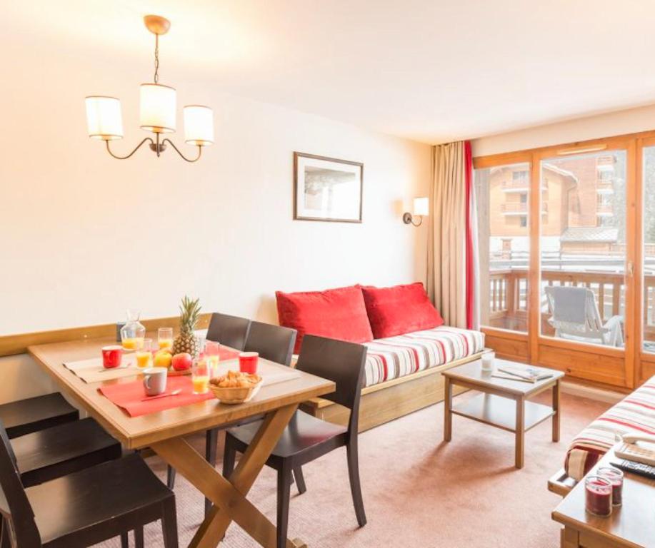 una sala de estar con una mesa y un sofá en Résidence L’Albane, en Vars