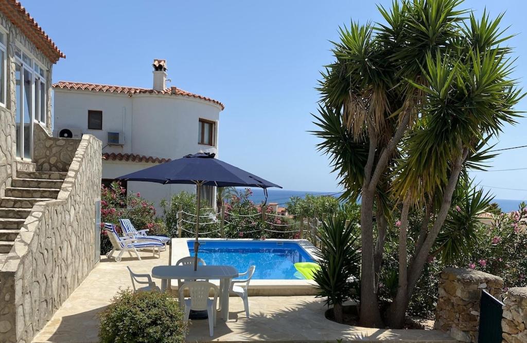 une terrasse avec une table, un parasol et une piscine dans l'établissement Villa França Air conditioned villa with sea view, WiFi, and private pool, à Alcossebre