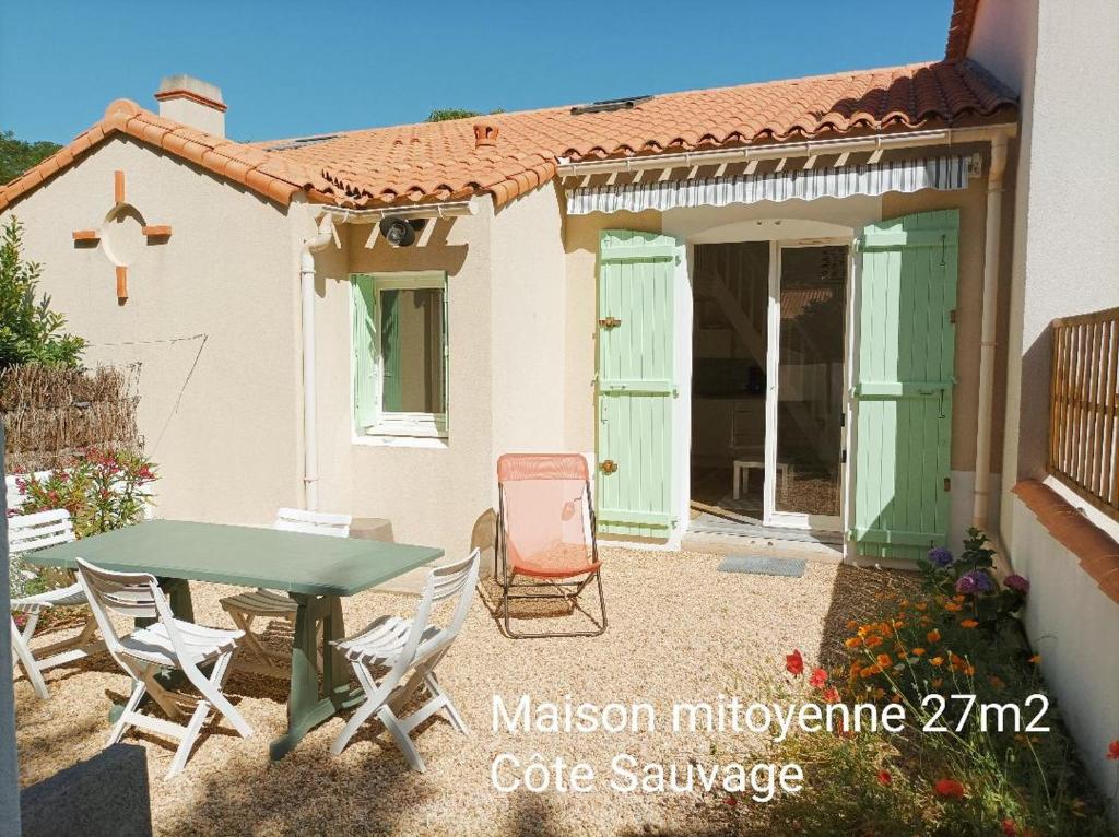 une terrasse avec une table et des chaises ainsi qu'une maison dans l'établissement Maison Bord de mer à Noirmoutier, à Barbâtre
