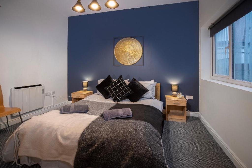 - une chambre avec un grand lit et un mur bleu dans l'établissement Bank Street Apartment 6, à Blackpool