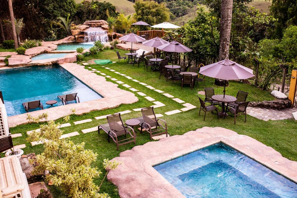 een uitzicht over een zwembad met tafels, stoelen en parasols bij Hotel Fazenda Horizonte Belo in Brumadinho